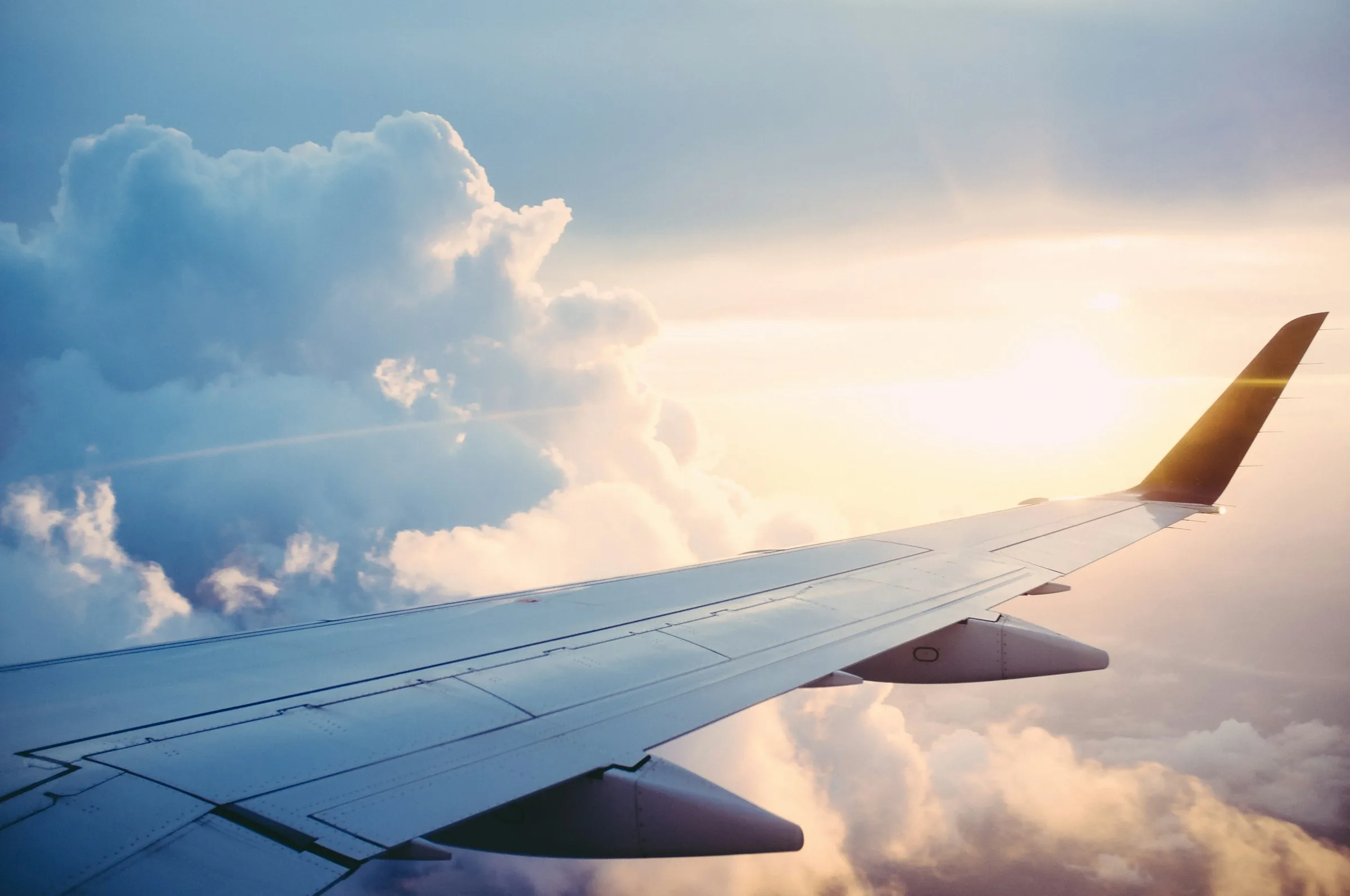 Airplane wing above golden clouds at altitude
